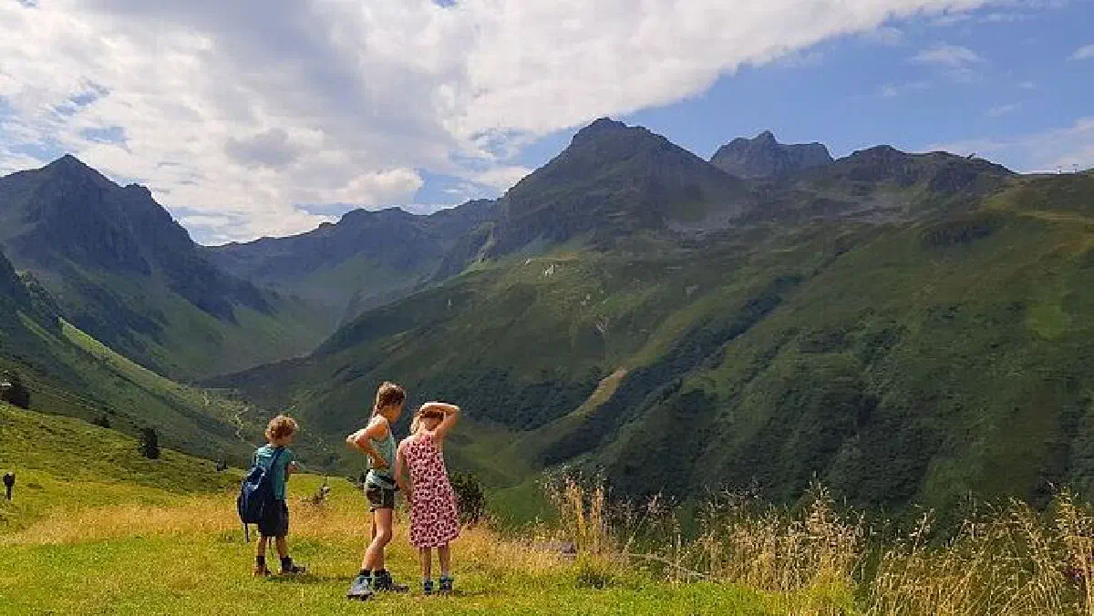 Vakantiefoto van het gezin van Anna uit Castricum. De fotograaf kijkt mee over de schouders van drie kinderen, die uitzicht hebben over een indrukwekkende bergenpartij.